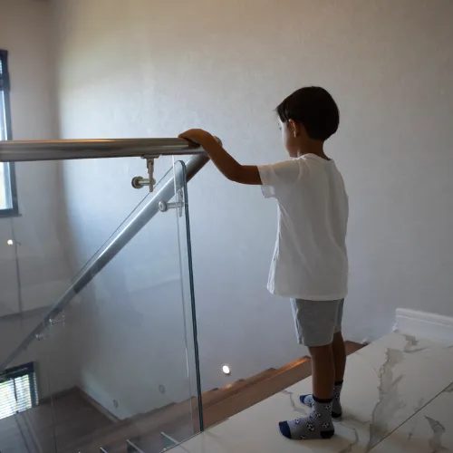 Main courante inox sur garde-corps en verre d'escalier
